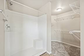 A white bathroom with a walk-in shower and a white toilet.