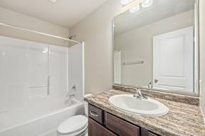A white bathroom with a marble countertop and a white toilet.