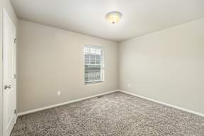 A room with a carpeted floor and a window.