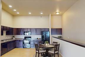 A kitchen with dark brown cabinets and a black refrigerator.