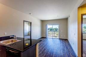 a kitchen and living room with a door to a balcony