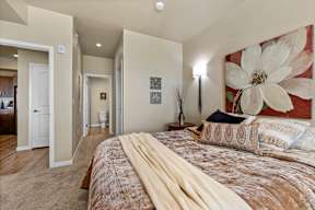 A bedroom with a large bed and a painting on the wall.