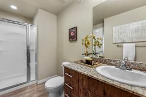 A bathroom with a toilet, sink, and a glass shower door.