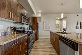 A kitchen with dark wood cabinets and granite countertops.