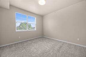 A room with a carpeted floor and a window with blinds.