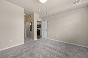 A spacious room with a carpeted floor and a ceiling fan.