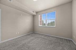 A room with a carpeted floor and a window with blinds.