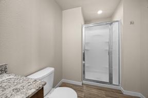 A bathroom with a toilet, sink, and shower.