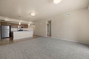 A spacious living room with a kitchen area in the background.