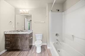 A white toilet sits in a bathroom next to a sink and a bathtub.