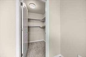 A small, empty room with a carpeted floor and a doorway leading to another room.