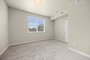 Empty room with a window and carpeted floor.