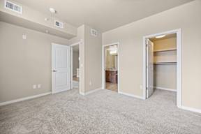 A spacious room with a carpeted floor and a doorway leading to another room.