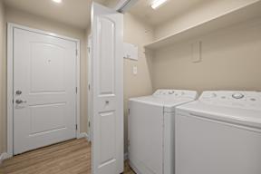 A white door is open to a laundry room with two washing machines.