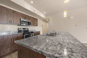 A kitchen with a granite countertop and wooden cabinets.