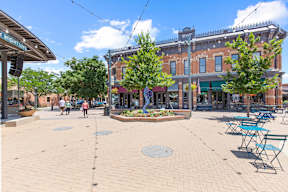 A sunny day in a town square with people walking and a building with a sign that says "The High Line".