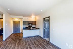 an empty living room with a kitchen and blue doors