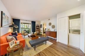 Furnished living room with open closet door showing stack-able washer and dryer