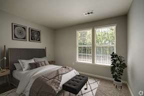 A bedroom with a bed, a bench, and two wall art pieces.