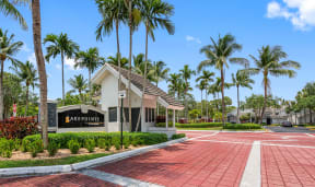 a building with palm trees in front of it and a red sidewalk