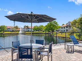 A patio with a table and chairs overlooking a pool.