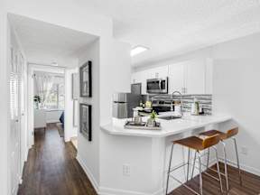 A kitchen with white cabinets and a white island with brown stools.
