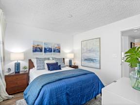 A bedroom with a large bed and a painting on the wall.