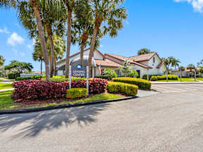 A Leasing Center is surrounded by palm trees and red bushes.