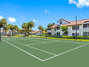 A tennis court with white lines on a green surface.