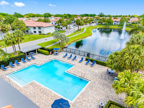 A large swimming pool surrounded by a fence and palm trees.