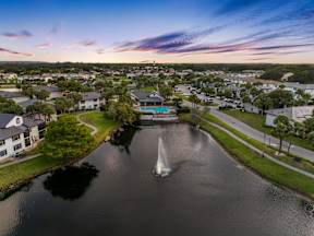 A fountain in the middle of a lake in a residential area.
