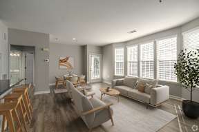 A modern living room with a grey sofa, wooden chairs, and a coffee table.
