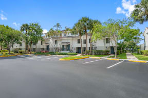 an empty parking lot in front of a building with palm trees