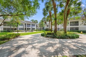 a courtyard with trees and a bench in front of a building