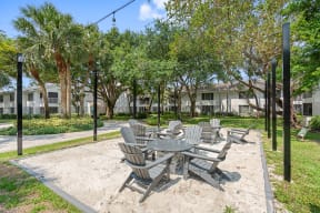 a sandy picnic area with tables and chairs in a park