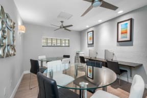 a dining room with a glass table and chairs and a ceiling fan