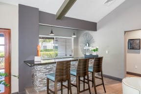 a bar with four chairs in a living room with a window
