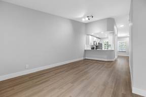 A spacious room with wooden flooring and white walls.