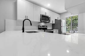 A modern kitchen with a marble countertop and stainless steel appliances.