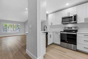 A kitchen with white cabinets and a wooden floor.
