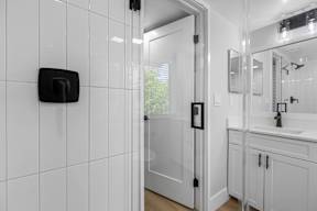 A white bathroom with a black soap dispenser on the wall.