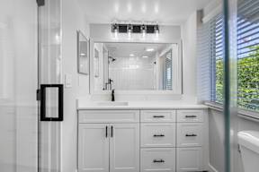 A bathroom with a white cabinet and a mirror above the sink.