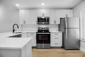 A modern kitchen with white cabinets and stainless steel appliances.