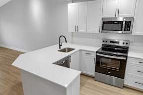 A modern kitchen with white cabinets and stainless steel appliances.