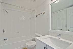 Bathroom with shower tub, toilet, sink, cabinets, and mirror