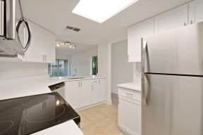 Kitchen with cabinets, stainless steel refrigerator, and microwave with pass-through to kitchen