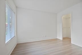 Bedroom with vinyl flooring, window and walk in closet