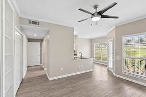 A spacious room with a ceiling fan and a kitchen area.
