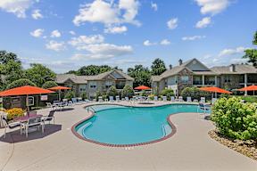 A swimming pool surrounded by lounge chairs and umbrellas in a residential area.