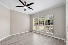 A room with a ceiling fan and a window with blinds.